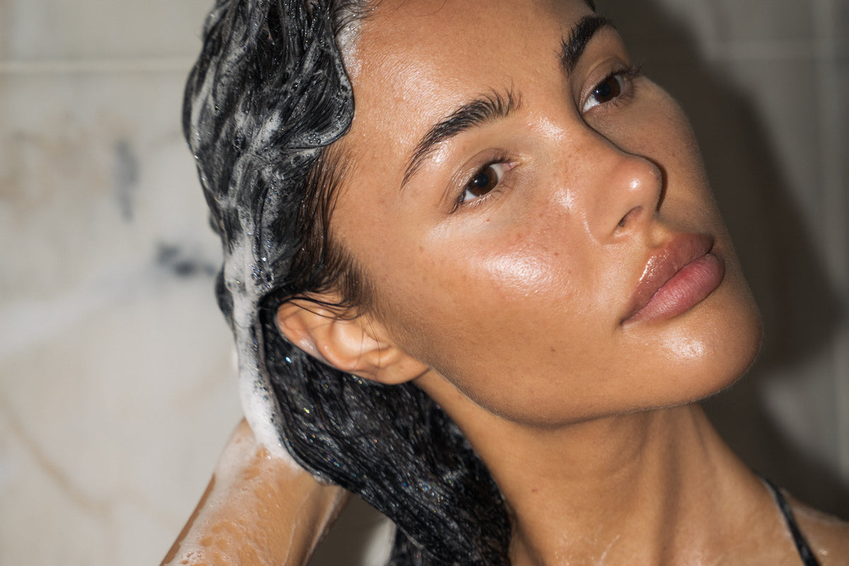 Woman shampooing dark hair in a marble shower, Hadrill Hair ritual